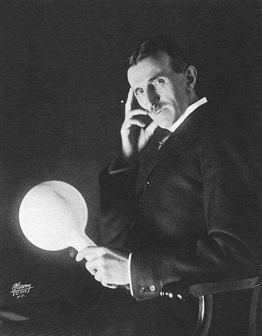 Nikola Tesla holding a light contraption. 